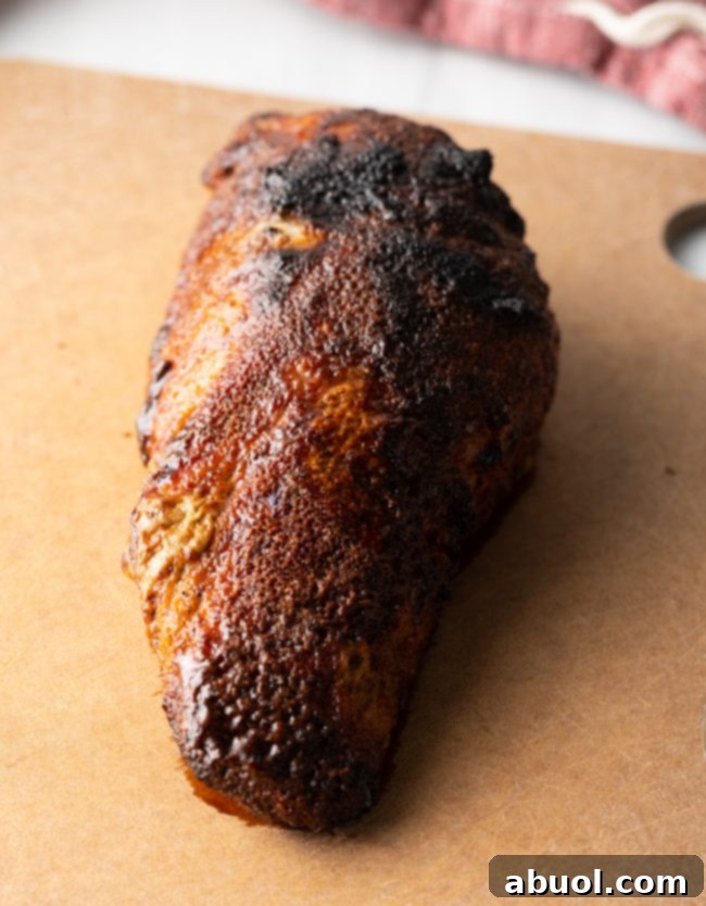 Pork tenderloin with a perfectly crusted exterior, resting on a wooden cutting board.