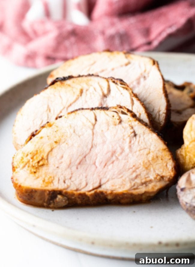 Close-up view of juicy slices of pork tenderloins on a white dinner plate, garnished beautifully.