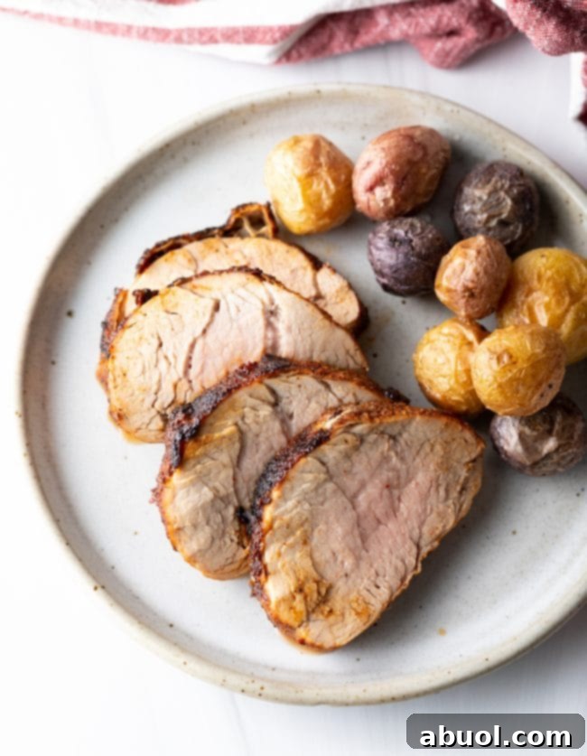 Top down view of white plate with slices of pork and whole baby potatoes, suggesting a delicious meal.