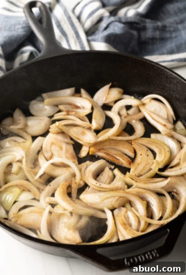 Sliced onions being sauteed in a skillet. 
