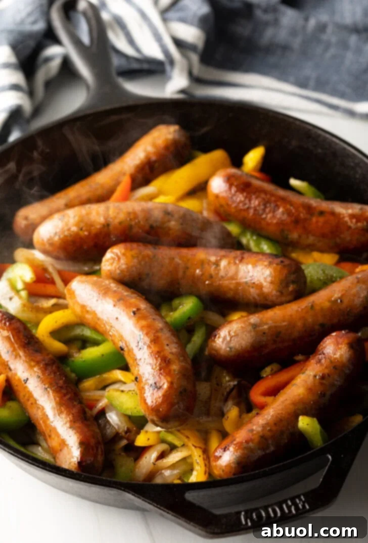Skillet filled with sauteed veggies and sausages. 