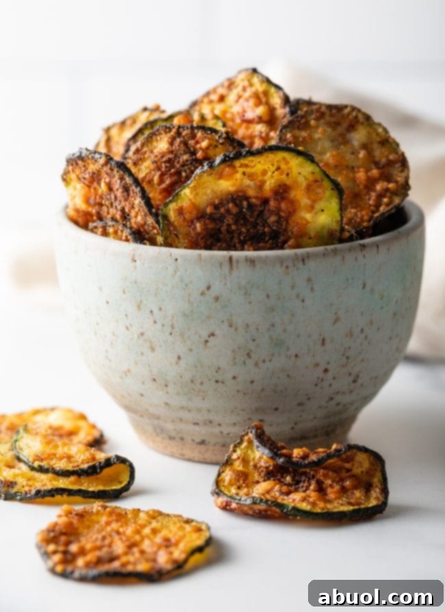 Crispy Air Fryer Zucchini Crisps 11 Speckled bowl overflowing with fried zucchini chips, a few chips laying around the bowl.