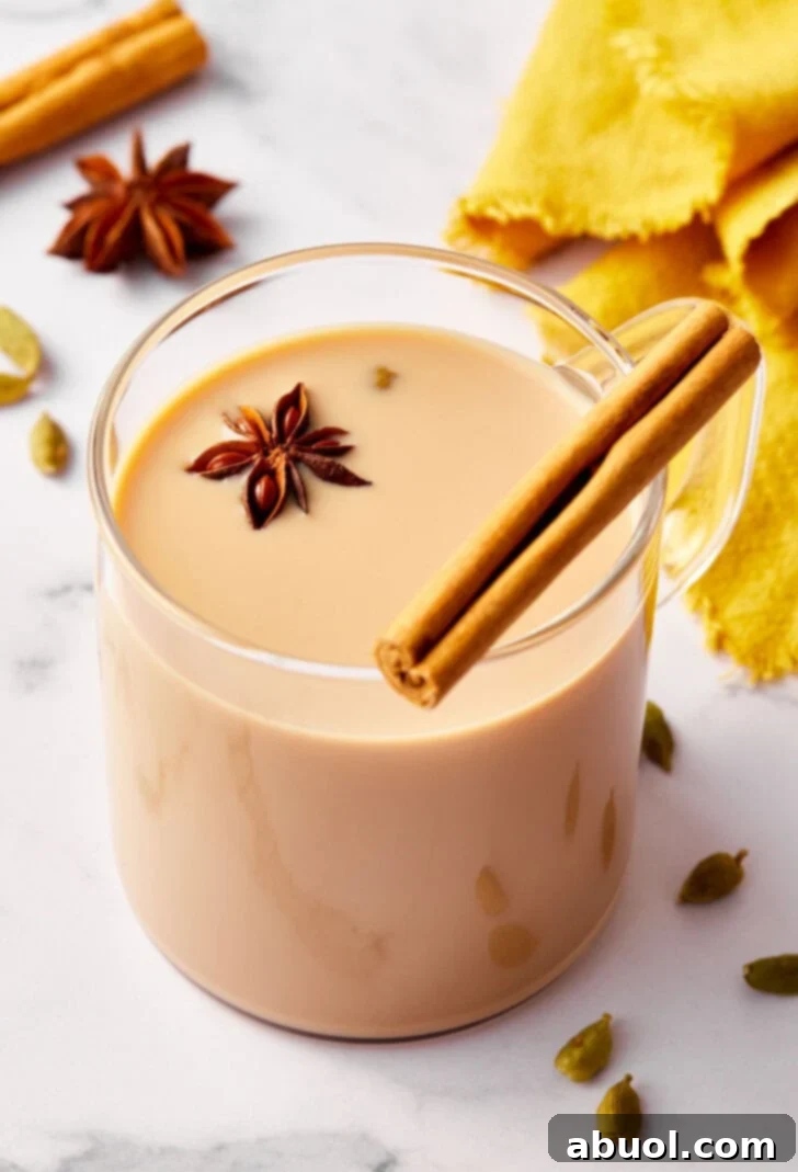 Closeup of chat tea in a glass mug garnished with a cinnamon stick.