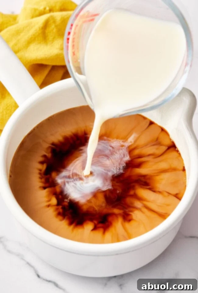 Milk being poured into a pot of chai tea recipe.
