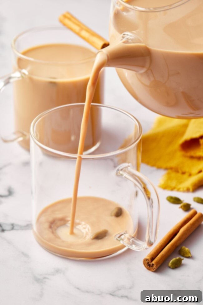 Pouring chai latte into clear mug.