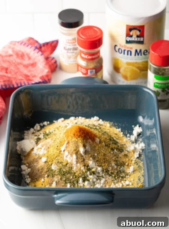 A close-up view of the dry fish fry seasoning mixture in a bowl, showcasing the blend of cornmeal, flour, and various spices. The texture is light and airy, ready to coat the fish.