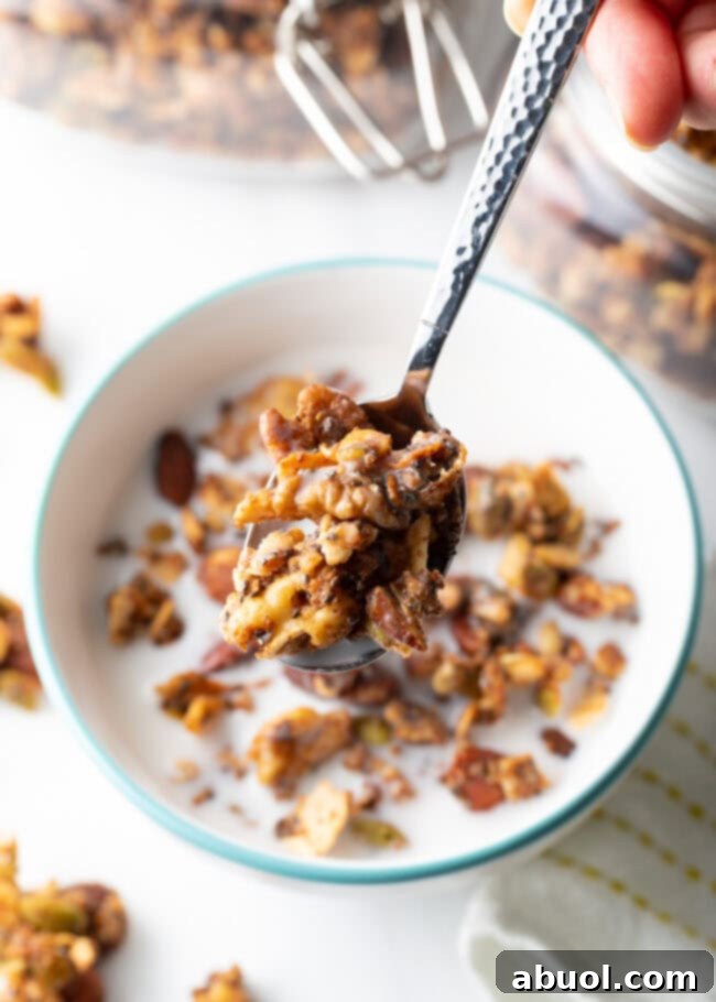 Ultimate Keto Granola Crunch 16 Top view spoon with granola and milk held to camera, over a bowl of granola.