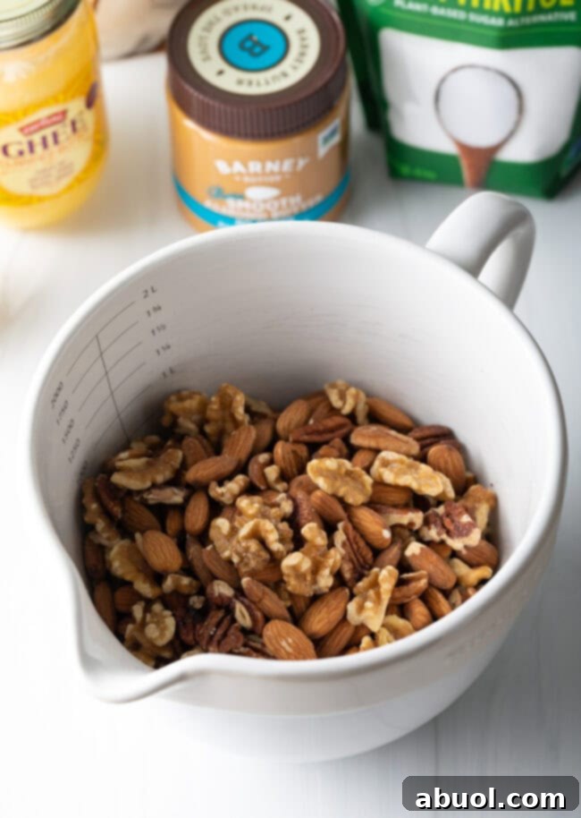 Ultimate Keto Granola Crunch 5 White mixing bowl with raw almonds, pecans, and walnuts.