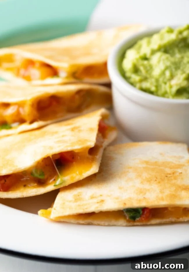 Pieces of shrimp quesadilla on a plate, with a small bowl of guacamole. 