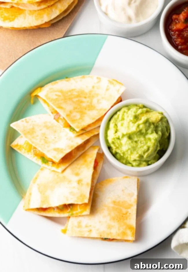 Top down view four triangles of quesadilla on a plate with ramekin of guacamole.