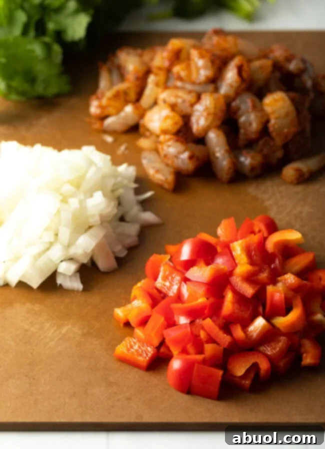 Piles of chopped ingredients on a cutting board: shrimp, onion, red bell pepper.