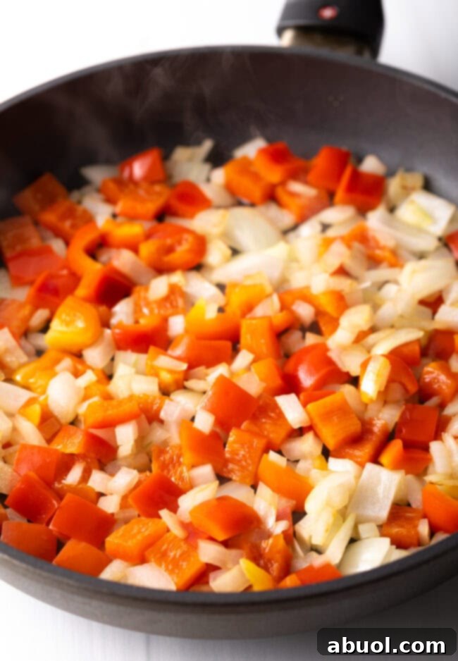 Chopped onions and red pepper in a skillet.