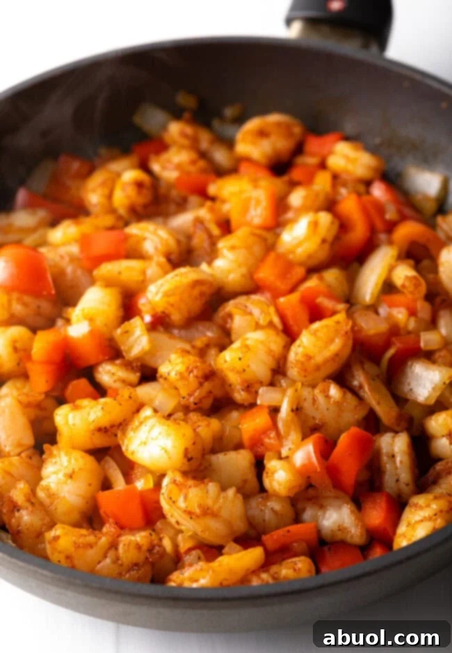Chopped onions, bell peppers and shrimp in the skillet. 