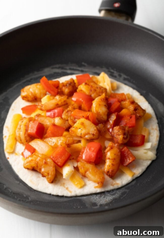 Skillet with tortillas, topped with cheese, peppers and shrimp.