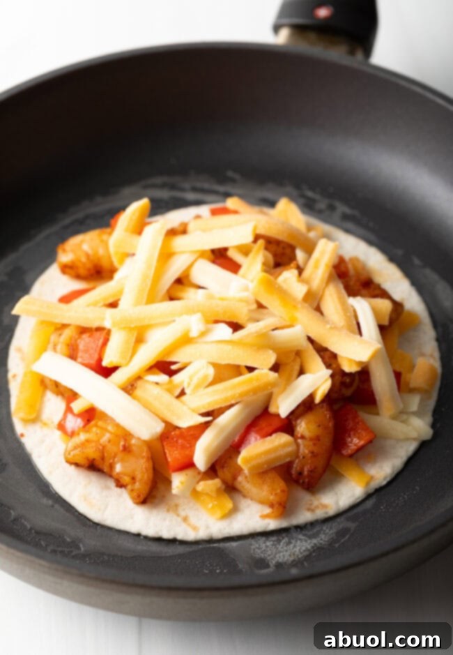 More cheese added to tortilla in a skillet.