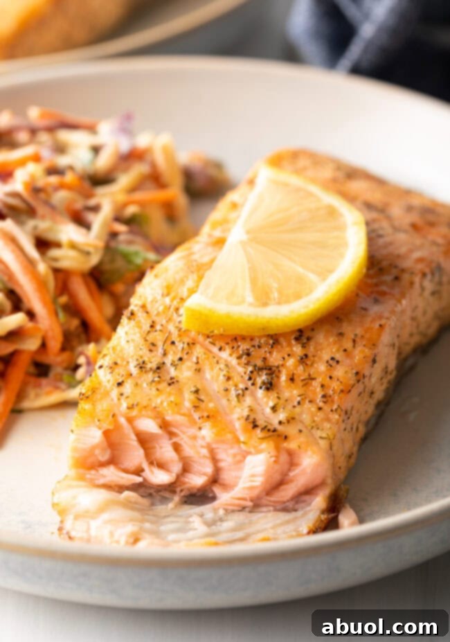 A delicious piece of air-fried salmon with a bite taken out, resting on a plate.