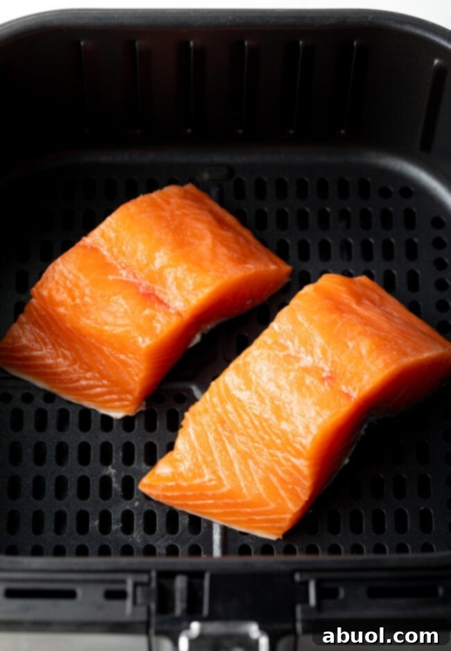 Two uncooked salmon fillets ready to be placed in the air fryer basket.