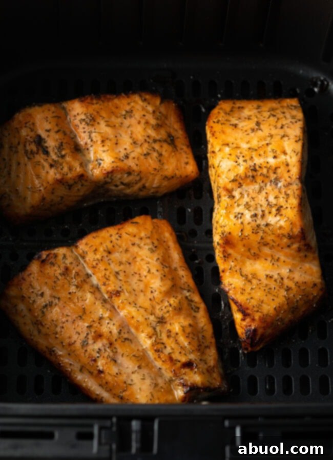Perfectly cooked salmon fillet with crispy skin, resting in the air fryer after cooking.