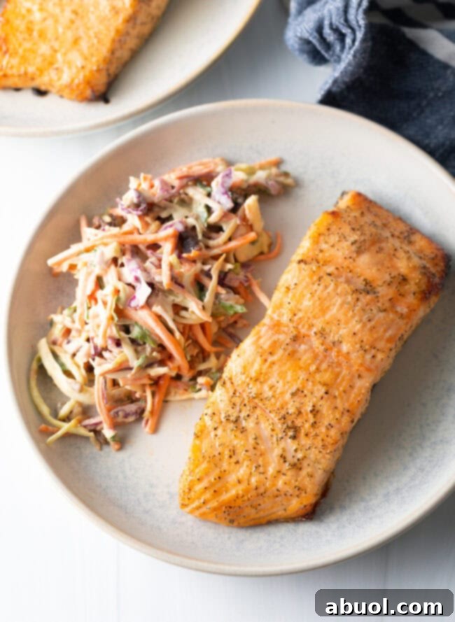 Top-down view of air-fried salmon served on a plate with fresh coleslaw.