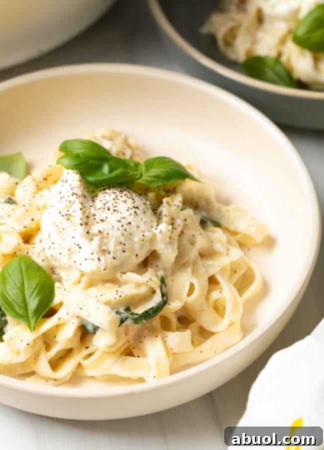 Final plated view of a bowl of lemon ricotta pasta, garnished with fresh basil leaves.