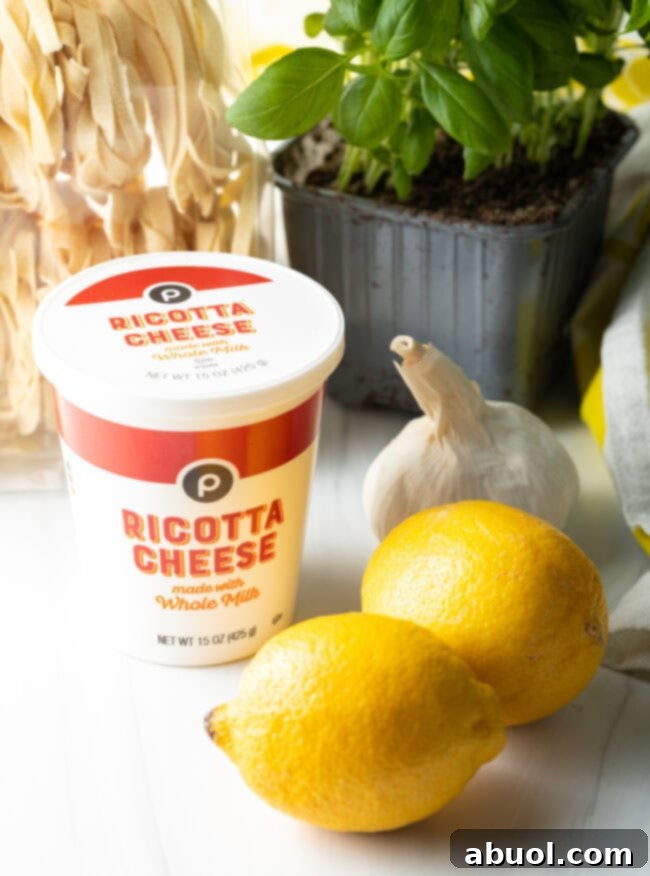 Essential ingredients for lemon ricotta pasta: Ricotta cheese, fresh lemons, garlic, and basil with dried fettuccine noodles.
