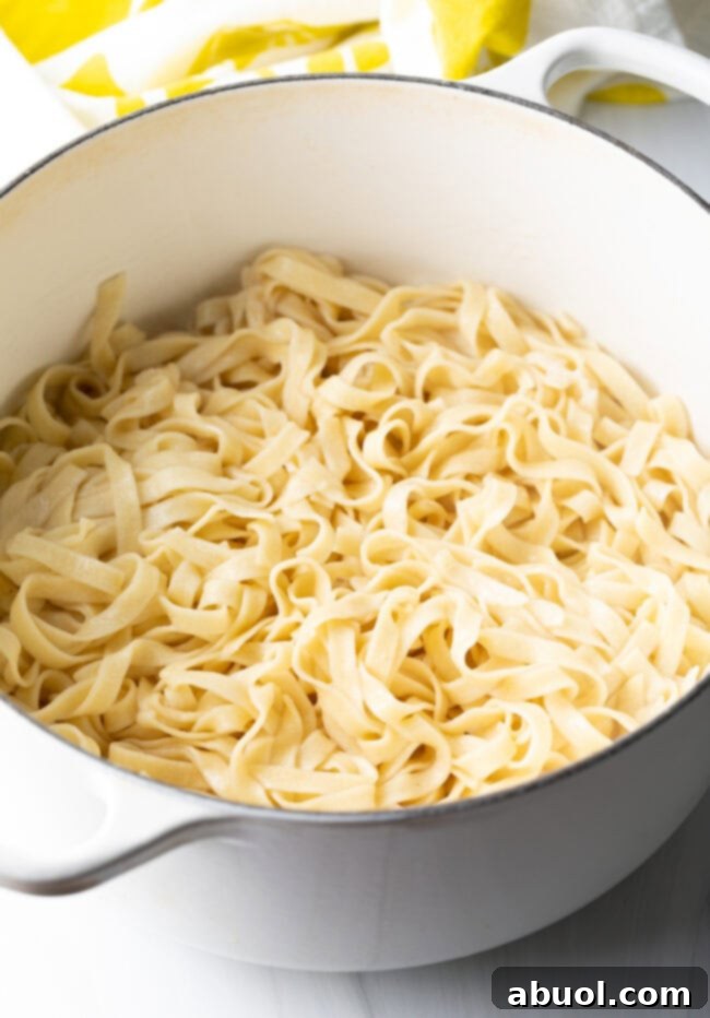 Large pot of perfectly cooked fettuccine noodles, with just enough starchy water remaining.