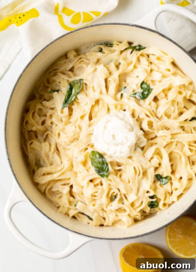 Top-down view of a large pot of fettuccine noodles coated in a creamy ricotta and lemon sauce, ready to be served.