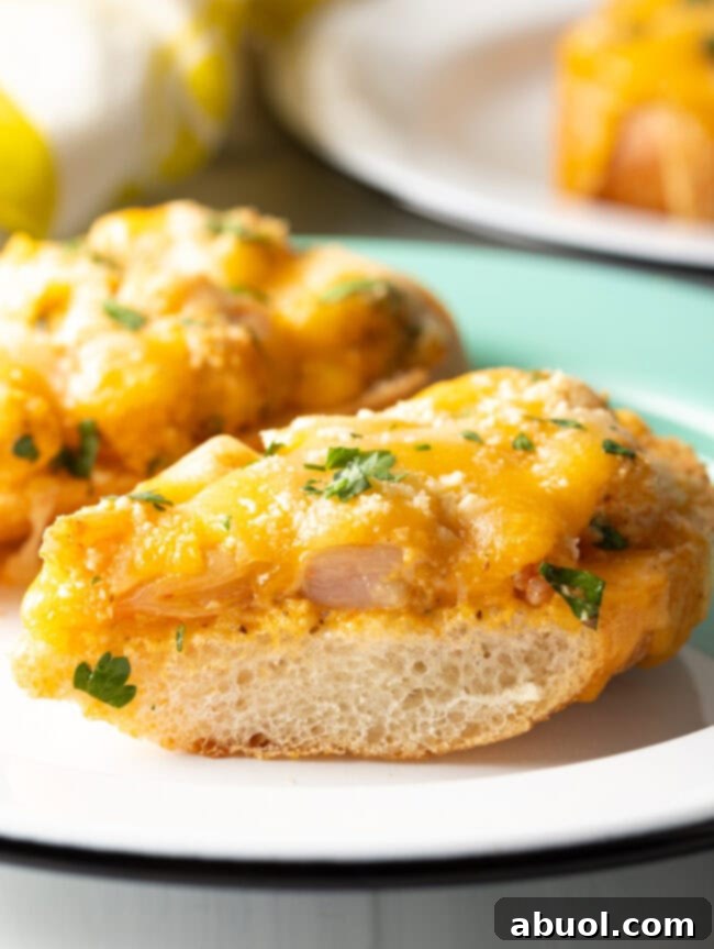 Close-up view of a baked toast slice generously topped with spicy shrimp and melted cheese, garnished with fresh herbs.