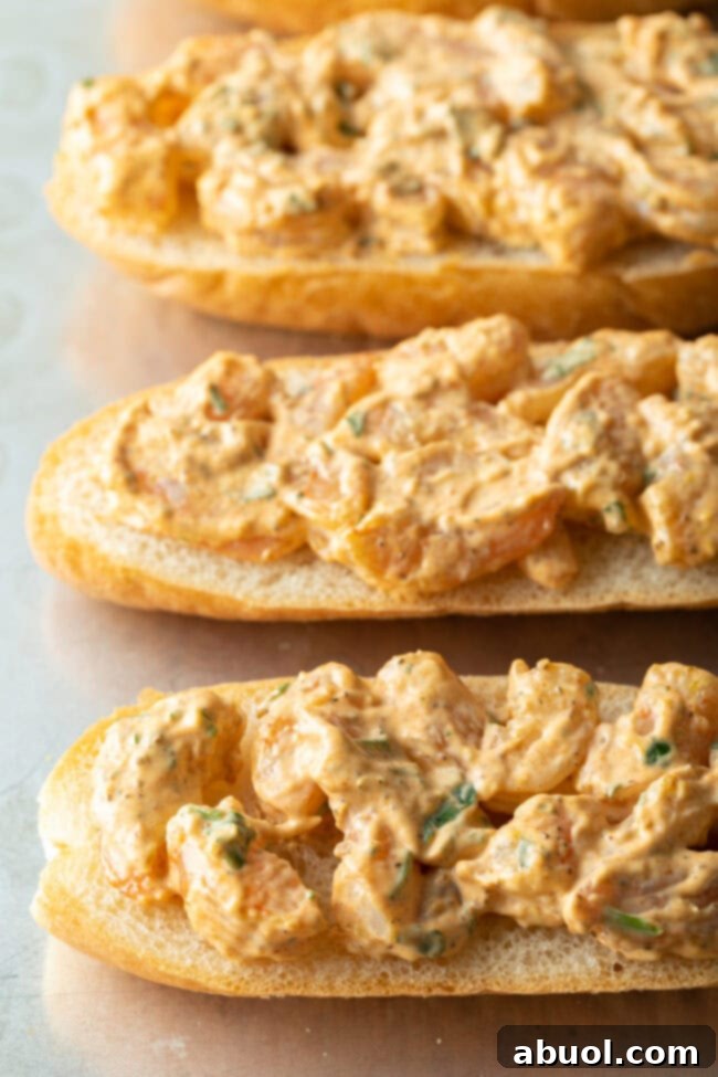 Four pieces of French baguette with the savory shrimp and mayonnaise mixture spread evenly across their surfaces.