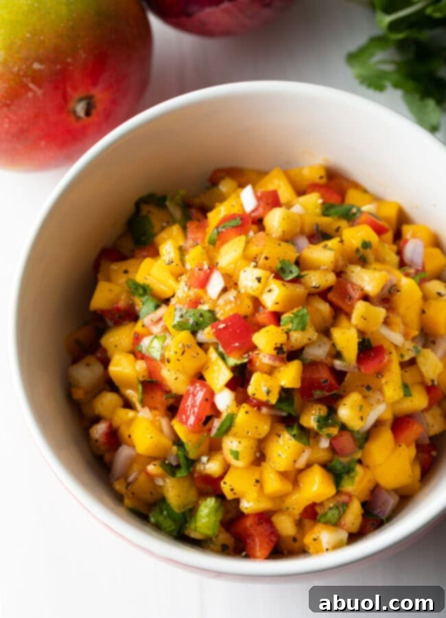 Top view bowl of vibrant peach mango habanero salsa, showcasing fresh fruit and pepper chunks.