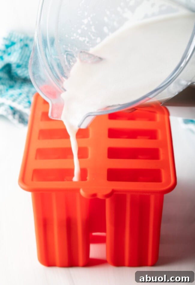 Pouring the blended coconut milk mixture into individual popsicle molds.