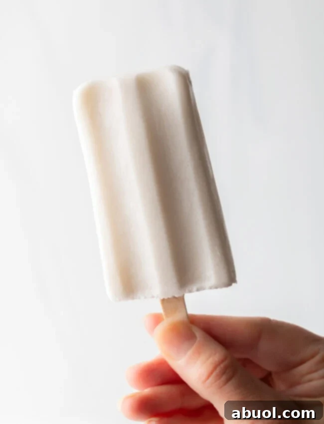 A hand holding a perfectly released coconut milk popsicle, ready to be enjoyed.