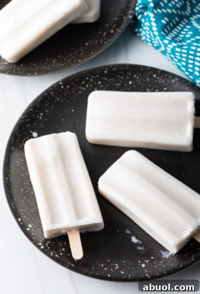 Top-down view of three dairy-free coconut popsicles arranged artfully on a plate.