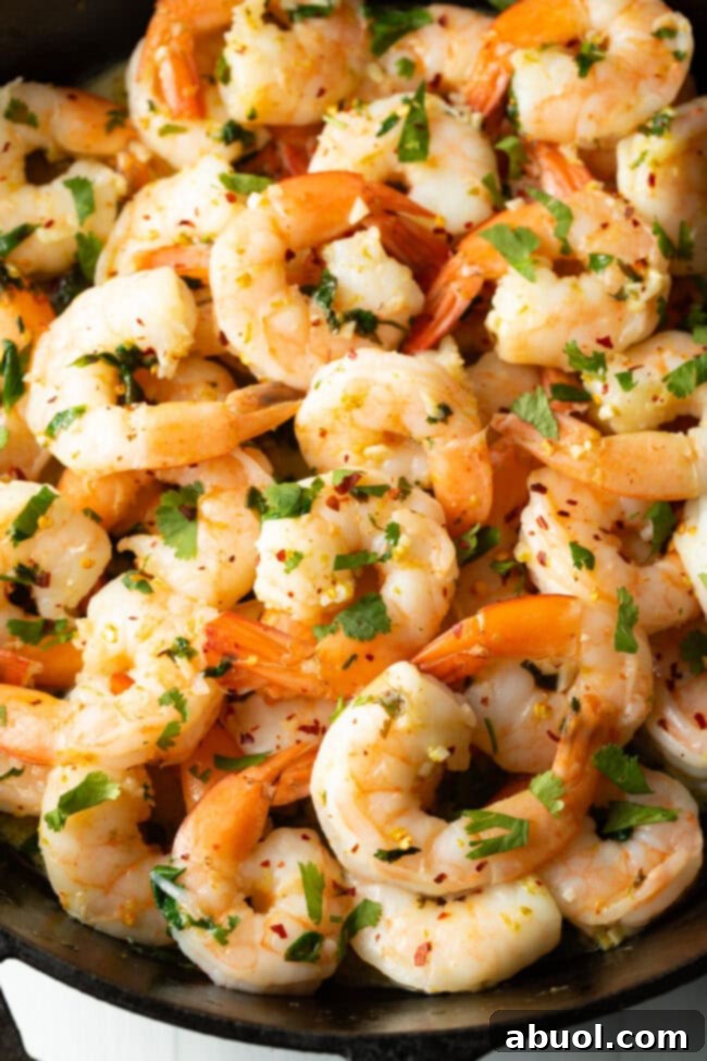 Close-up view of cooked shrimp infused with garlic and fresh cilantro.