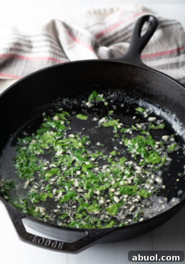 Cast iron skillet with melting butter, minced garlic, and fresh cilantro.