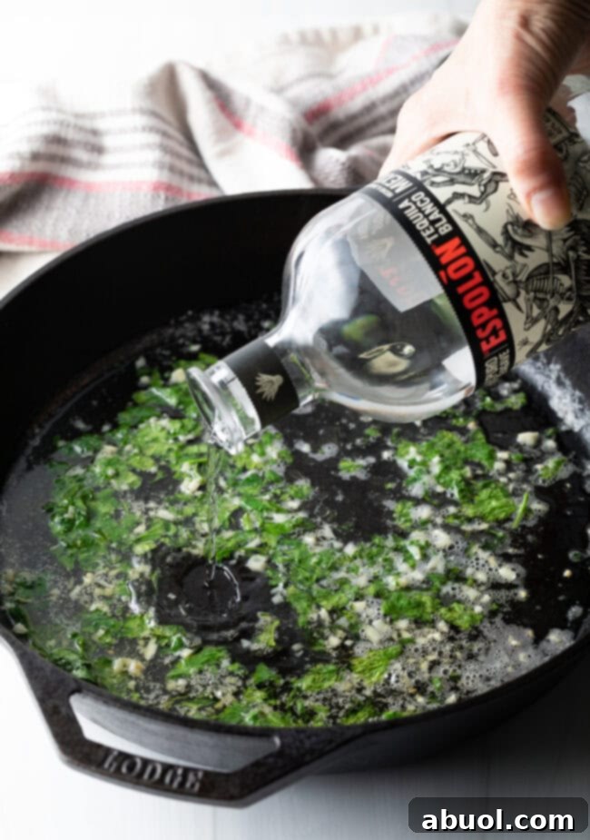 Pouring tequila into a hot cast iron skillet, creating a flavorful base for shrimp.
