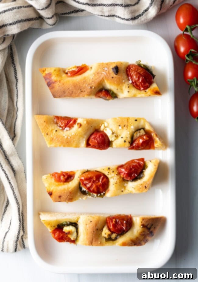 Top-down view of four perfect pieces of tomato basil focaccia bread arranged on a white platter, ready to be served.