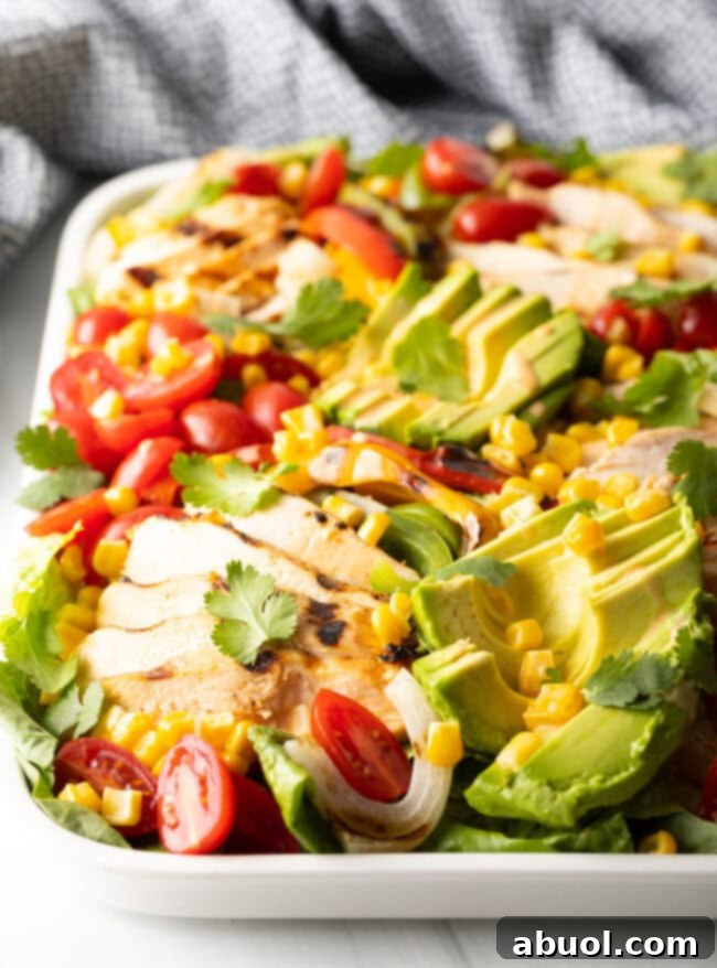 Close-up of grilled chicken and sliced bell peppers on a cutting board, ready for salad assembly.