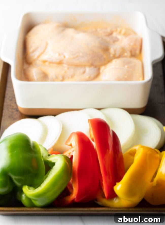 Sliced raw vegetables and raw chicken on a platter, ready for grilling.