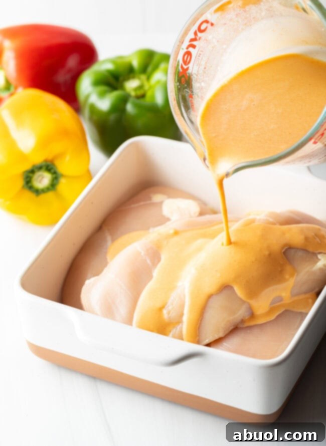 Marinade being poured over raw chicken pieces in a dish.