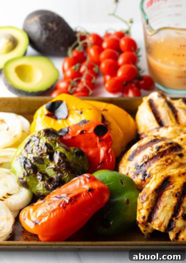 Closeup of grilled chicken and vibrant vegetables with grill marks.