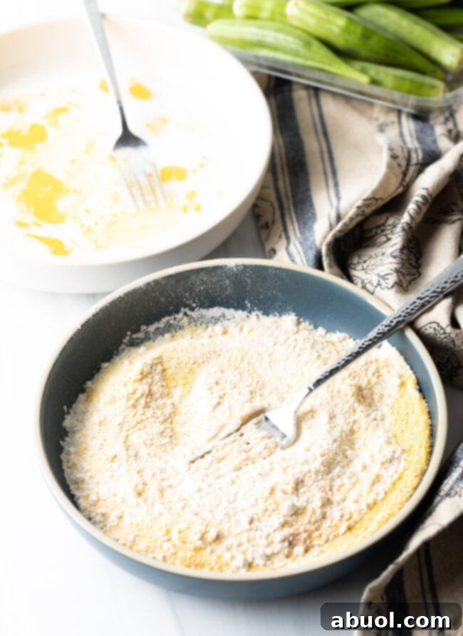 Close-up of the egg and milk mixture being whisked in a bowl, forming the essential binder for the okra.