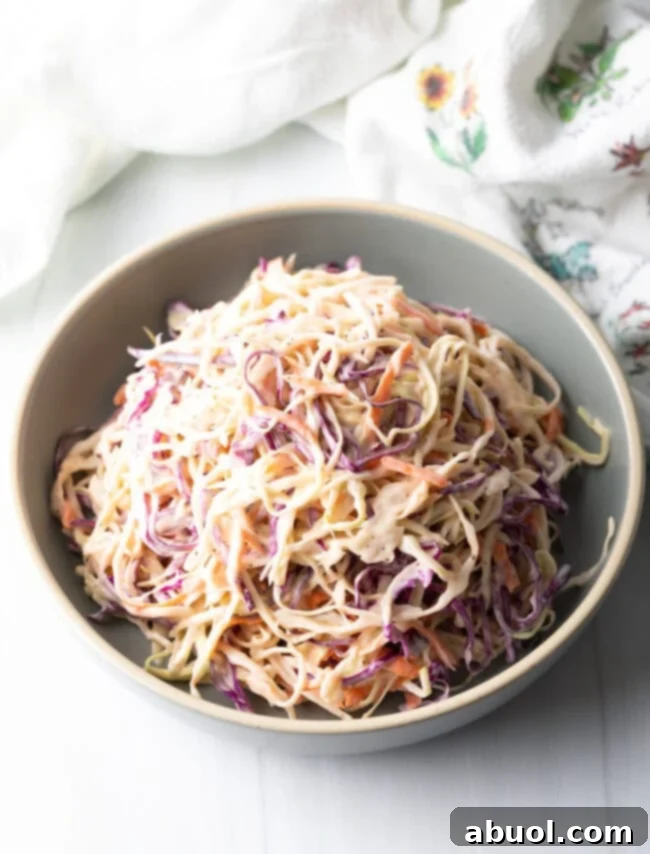 Top down view of a bowl filled with shredded coleslaw generously coated in creamy dressing.