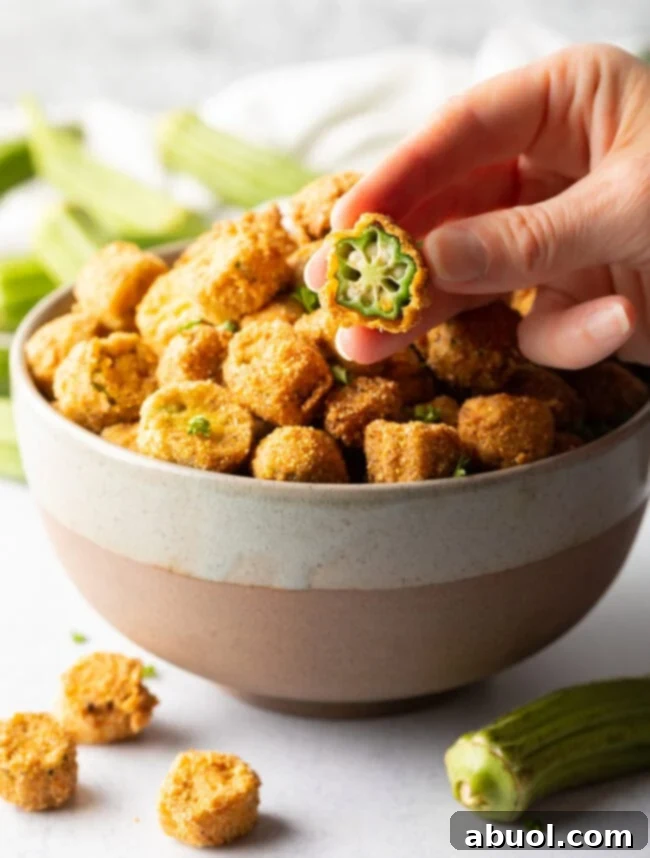 Hand holding sliced breaded okra peice to camera.