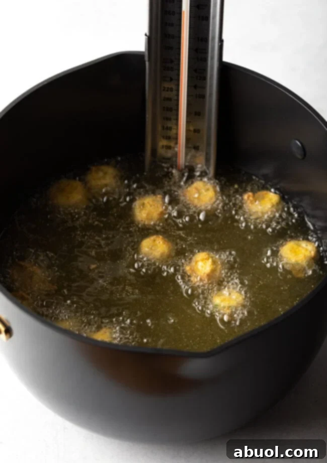 Hot oil in large pot, pieces of breaded okra frying.