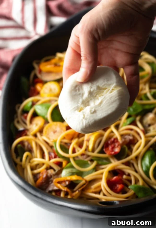 Hand adding ball of burrata cheese to the dish.