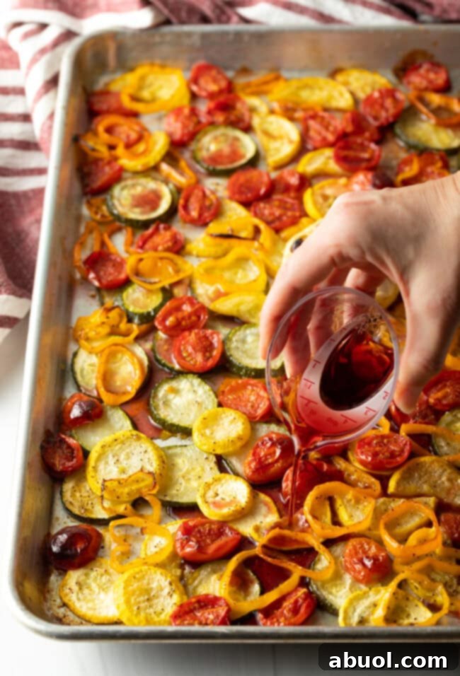 Hand pouring sauce base on roasted summer vegetables.