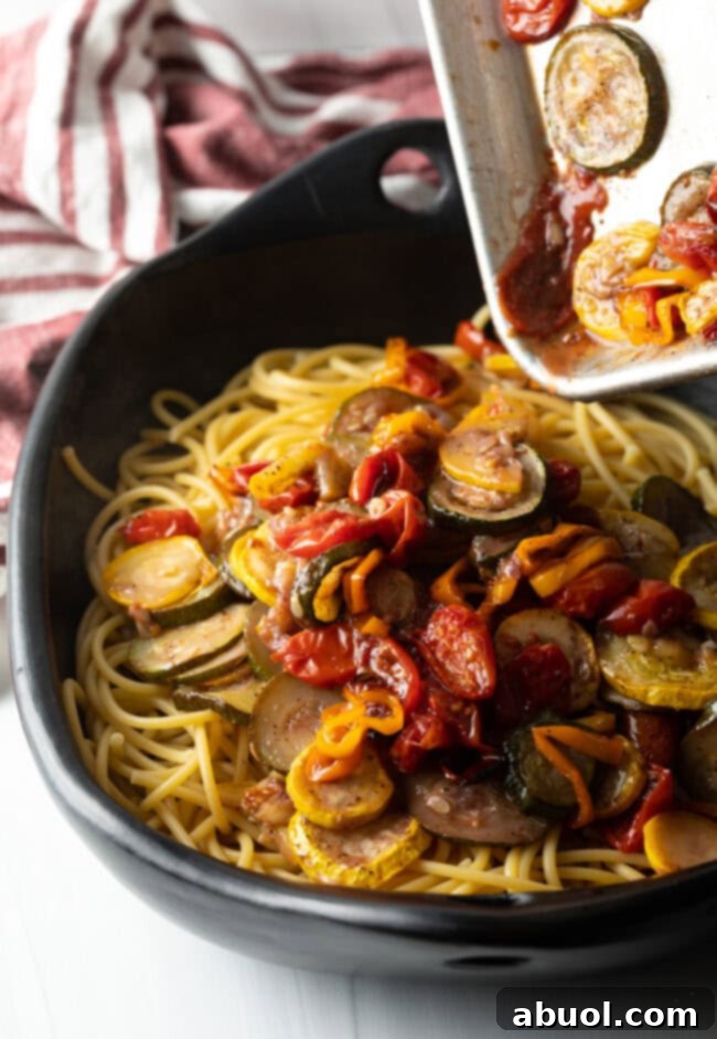 Pouring veggies and sauce over the spaghetti.