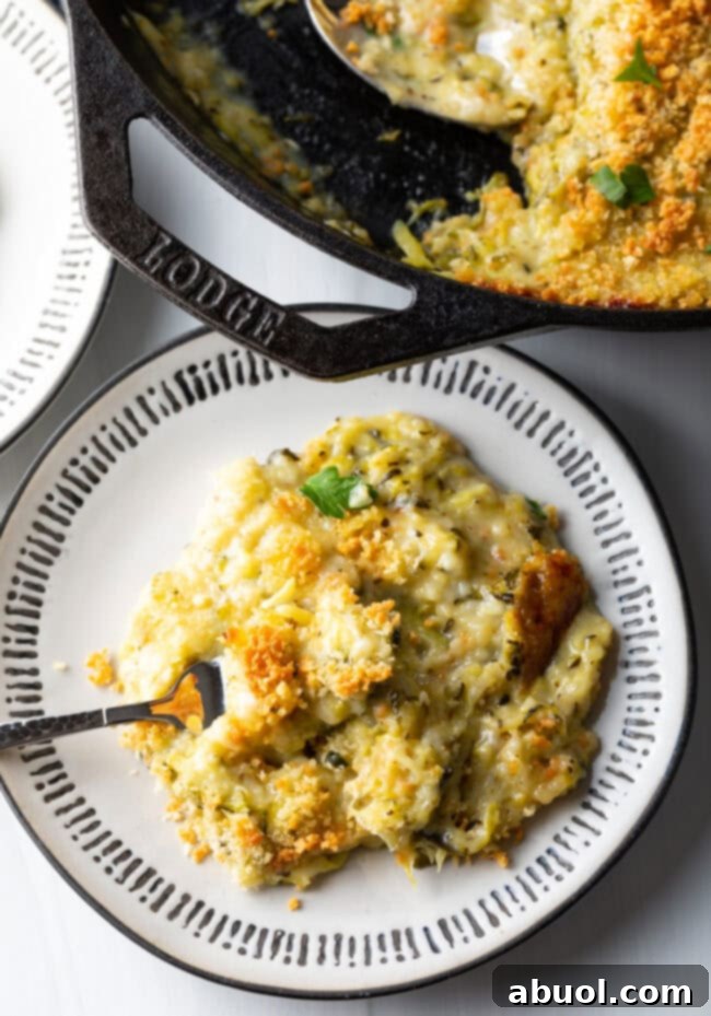 Close-up top-down view of a portion of cheesy zucchini casserole on a plate with a fork.
