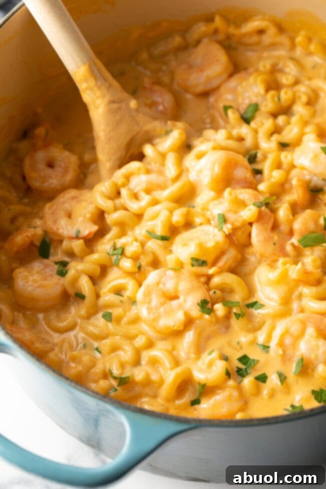 Closeup view of pot of macaroni and cheese with shrimp sprinkled with chopped parsley.